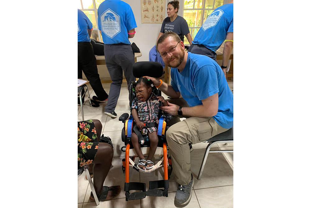 Male physical therapy professor tries to comfort Haitian child crying in wheelchair