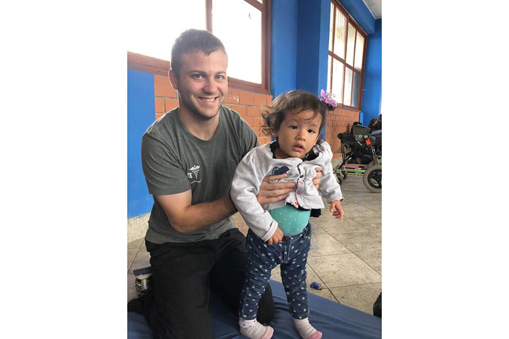 Male physical therapy student plays with young girl